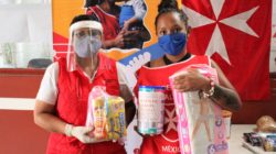 A woman enrolled in our infant HIV prevention program stands with groceries and baby formula she has just received from a program we support. 