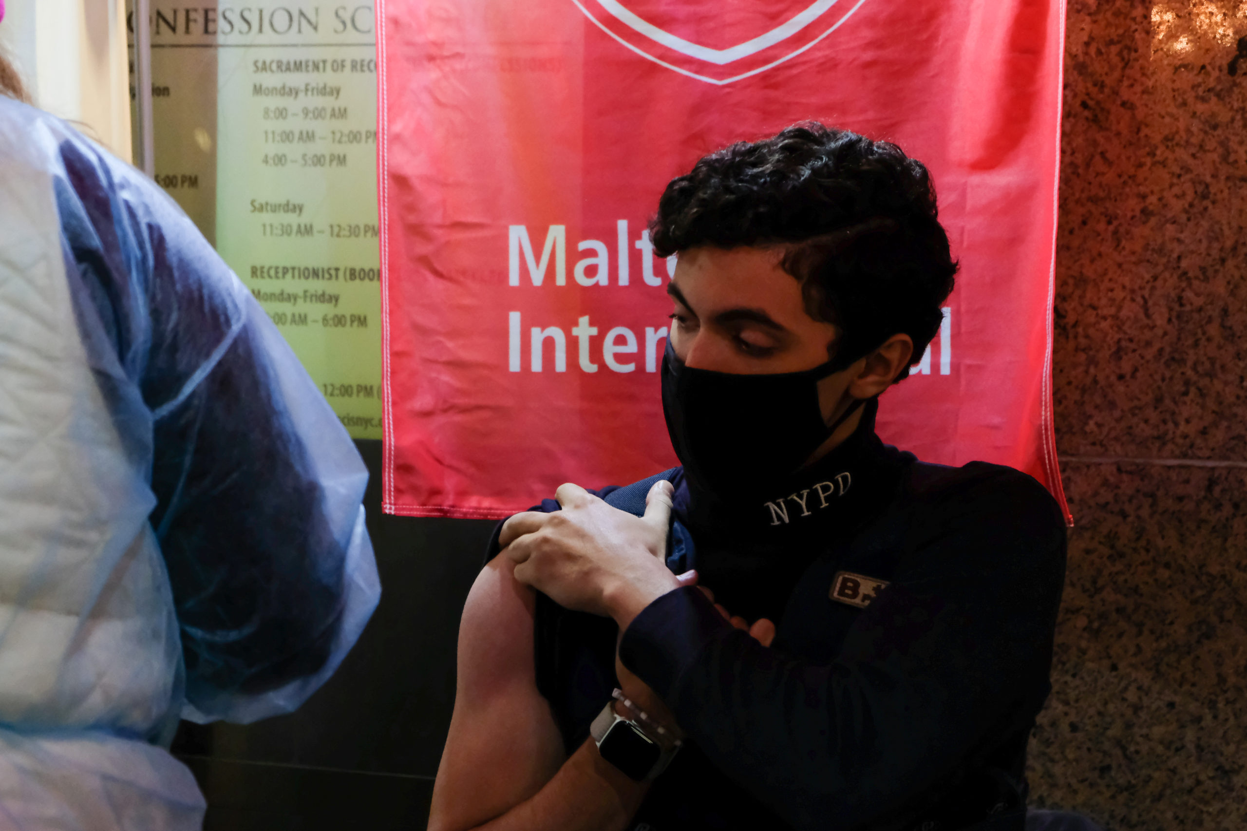 An NYPD officer receives a flu shot from Malteser International Americas.